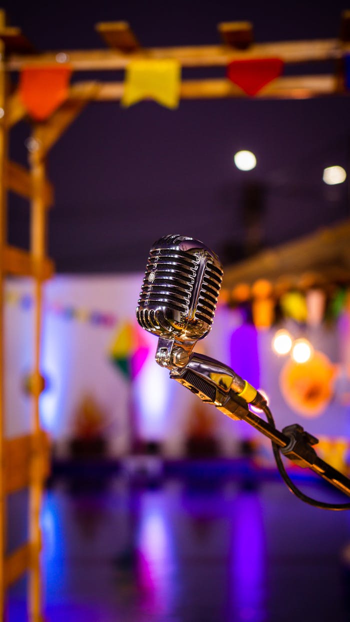 A classic microphone on stage with vibrant colors and lights in the background, capturing a lively event atmosphere.